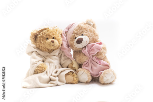 A pair of soft toy bears on a white background. Sleepy bear in a cap with a blanket and a bear in a dress. Concept of friendship, childhood, relationships, sleep, falling asleep, dreams. Horizontal.