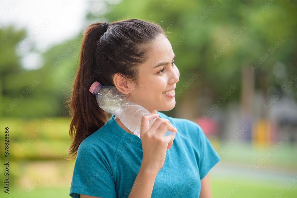 Fitness woman is drinking water after workout in park