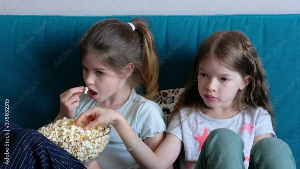 little children watching TV at home, eating popcorn little children watching TV at home, eating popcorn