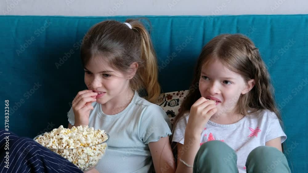 little children watching TV at home, eating popcorn and laughing little children watching TV at home, eating popcorn and laughing