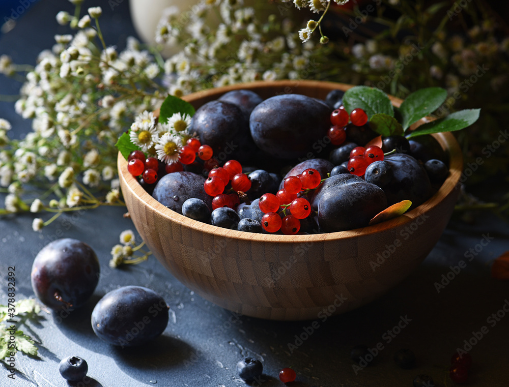 Ripe summer berries in a wooden bowl on a dark background Ripe summer berries in a wooden bowl on a dark background