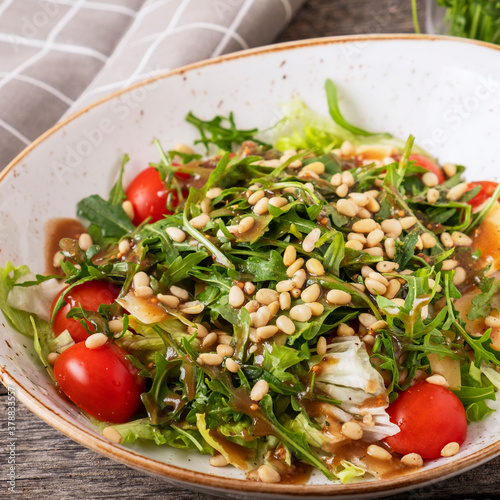 Dieta and healthy arugula salad with pine nuts, tomatoes and cheese. Closeup