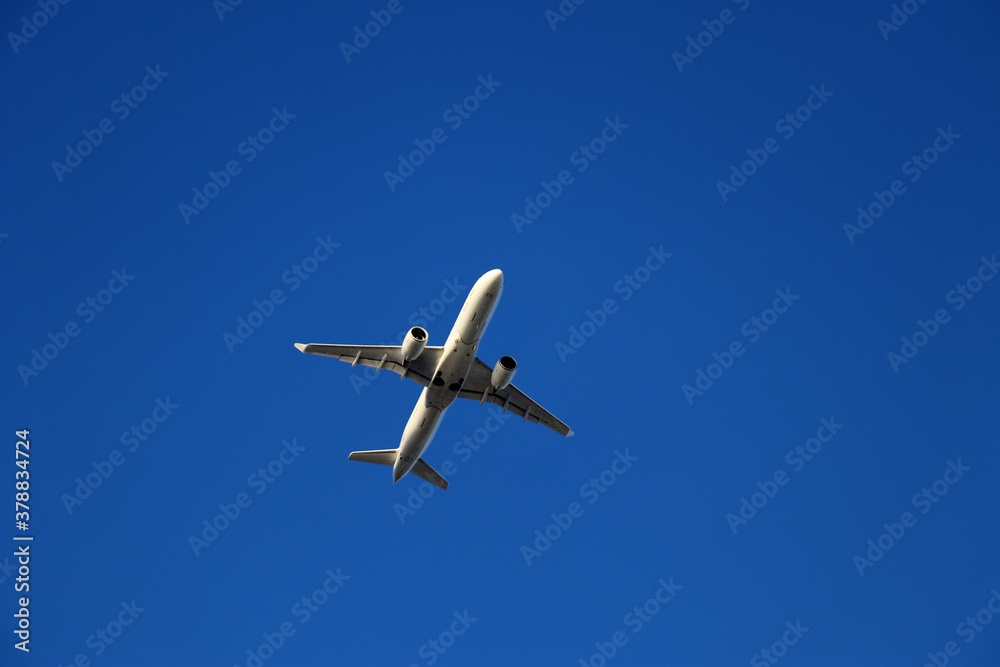 Airplane flying high in the clear blue sky - low angle view Airplane flying high in the clear blue sky - low angle view