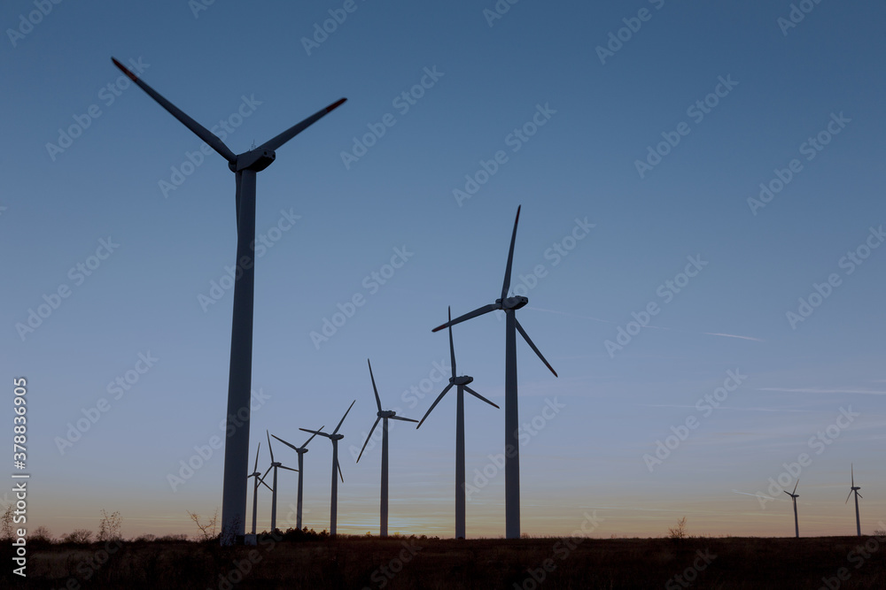 Wind Turbines at Dusk. Landscape sunset with windmills. Renewal source of electricity. Wind turbines field new technology for clean energy on mountain, sunset view with colorful twilight on sky. Wind Turbines at Dusk. Landscape sunset with windmills. Renewal source of electricity. Wind turbines field new technology for clean energy on mountain, sunset view with colorful twilight on sky.