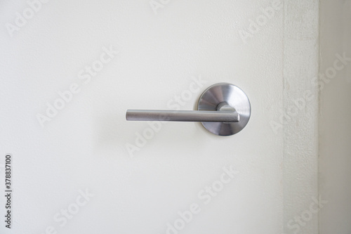 Close-up of a stainless steel door handle on indoor white door