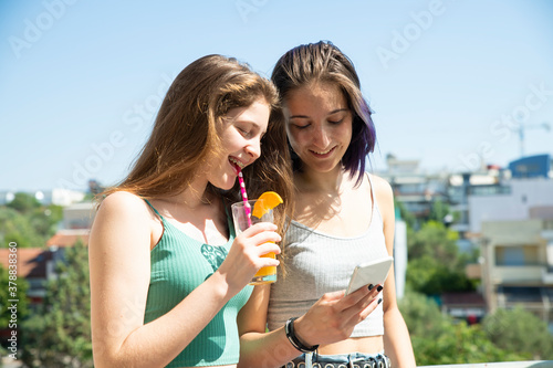 A Teenage Girl Drinking Her Fruit Juice and Her Sister Watching Her Mobile Phone