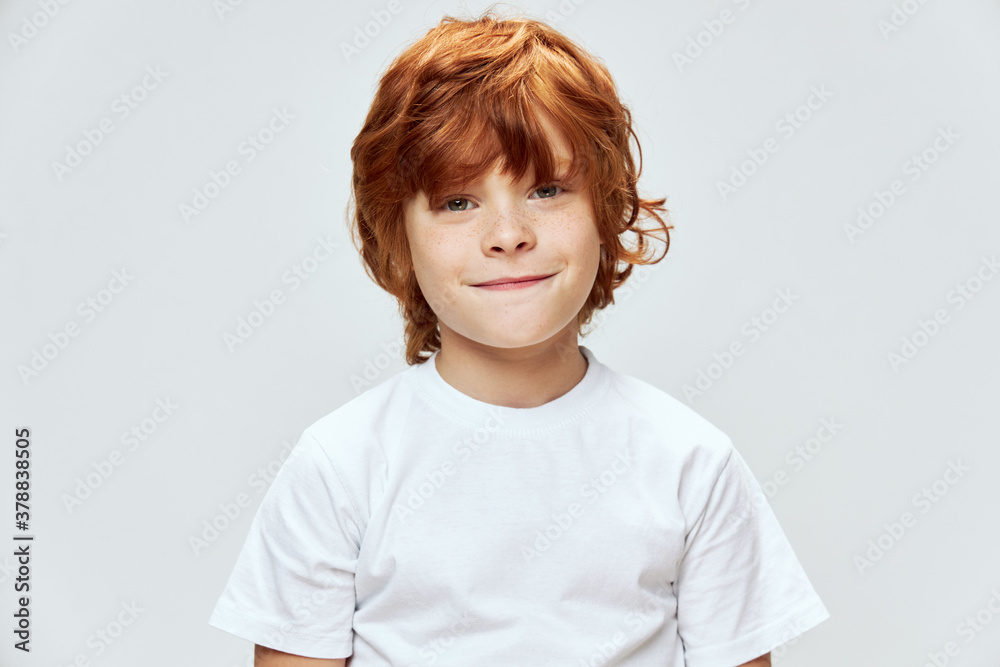 Red-haired boy looking ahead smile white t-shirt childhood cropped view Red-haired boy looking ahead smile white t-shirt childhood cropped view