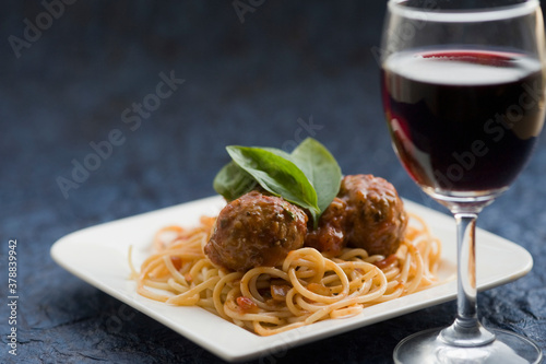 Close-up of spaghetti and meatballs with red wine