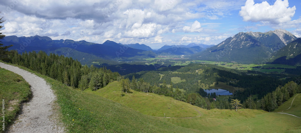 Panoramaaufnahme vom Hohen Kranzberg mit Blick auf die Benediktenwand und das Karwendelgebirge mit Schöttelkarspitz und der Soierngruppe sowie Wildensee