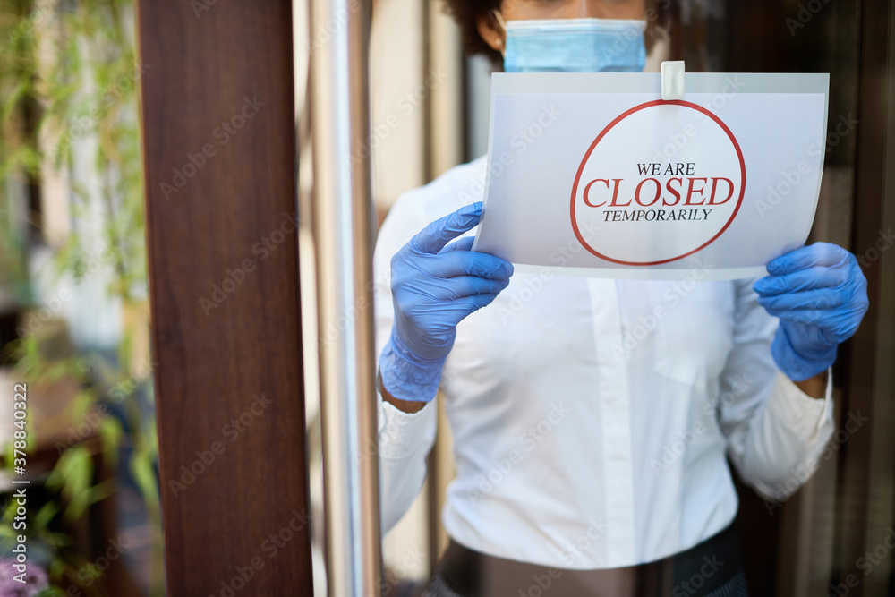 Φωτογραφία Close-up of cafe owner hanging closed sign due to COVID-19 pandemic