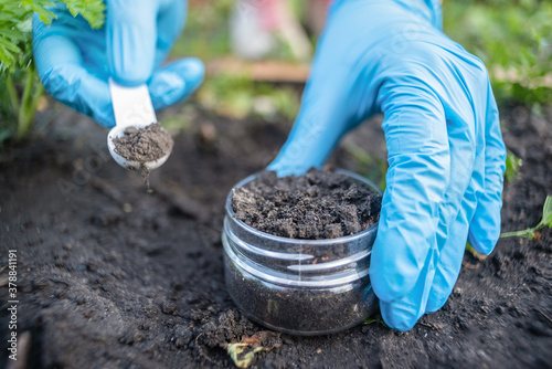A soil science concept. Scientist is holding in hands a jar with soil sample and scoop.