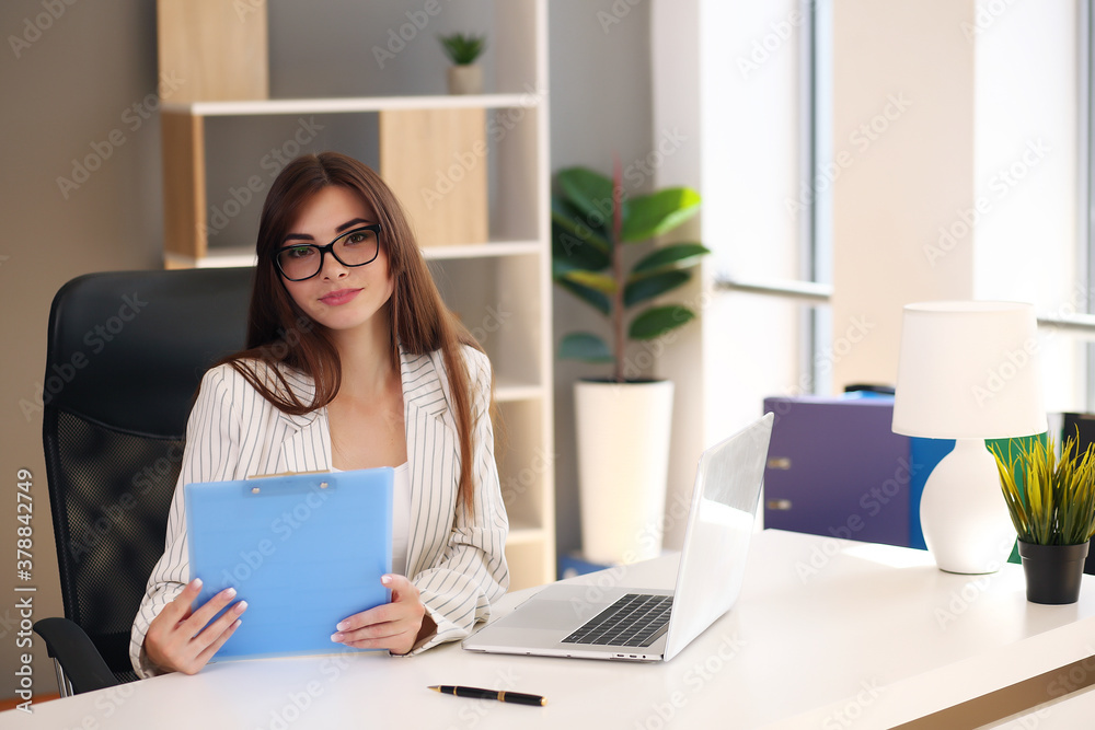 Young pretty brunette business woman with laptop in the office Young pretty brunette business woman with laptop in the office