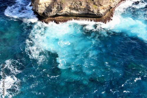 Clear blue ocean swirling around rocks on Nusa Penida Island, Bali, Indonesia