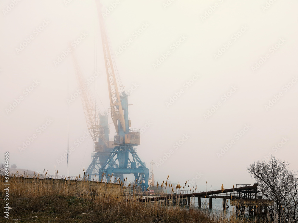 Harbor crane. Two old rusty cranes in an industrial port in the fog. Harbor crane. Two old rusty cranes in an industrial port in the fog.