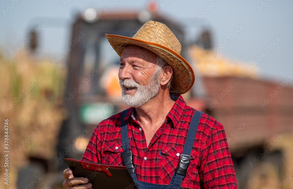 Portrait of senior farmer in front of tractor during corn harvest