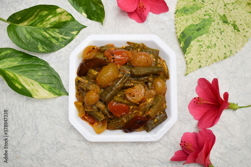 Top view of Indian vegetable curry Bhindi do pyaza made of whole big pieces of lady fingers and onions, a side dish north indian punjabi style gravy ki sabji. Decorated with flowers and leaves photo