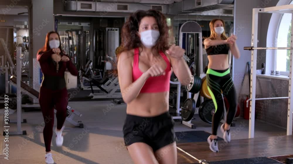 Group of Young beautiful female athletes wearing face masks doing Boxing warm-up aerobics in the gym. Fitness training workout.