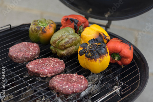 hamburger meat and peppers on black barbecue outside