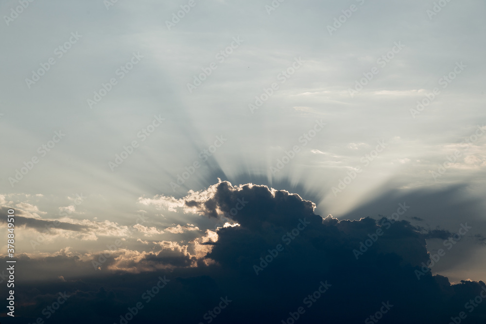 Orange light with sun rays and dark clouds on sky before sunset in the evening. Beautiful dramatic sky clouds with light rays at sunset. Natural landscape for background