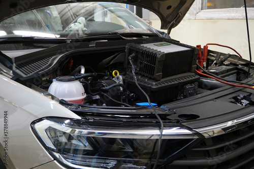 A modern car in a car service at a diagnostic post. The hood is open on the vehicle and diagnostic equipment is connected. © Орлов Александр