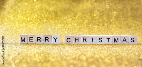 merry christmas lettering in wooden letters on a gold bokeh background