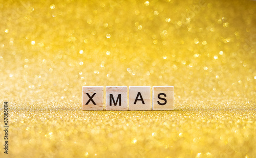 xmas lettering in wooden letters on a gold bokeh background