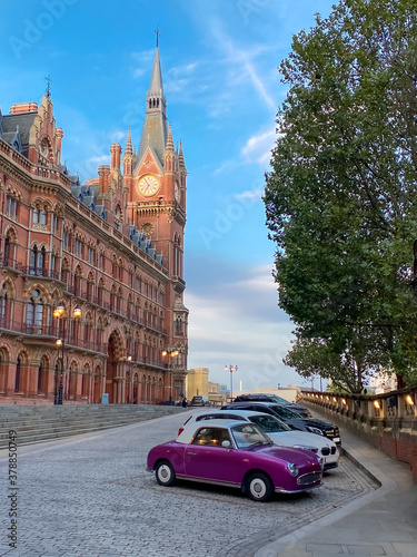  The clock tower of the famous Kings Cross St Pancras railway station and old car parking in London  England