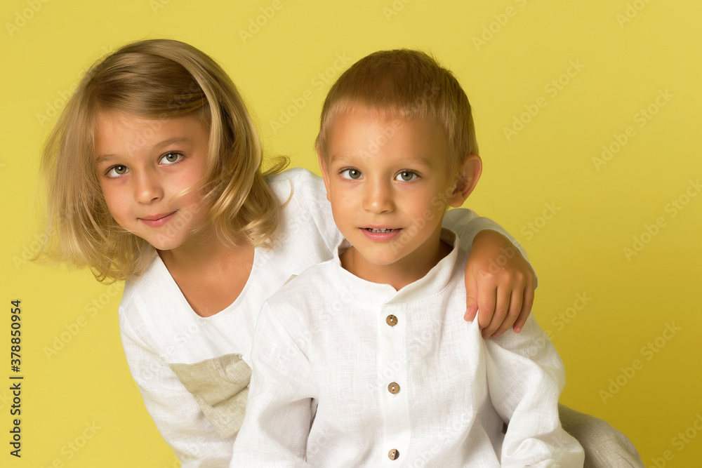 Younger brother with older sister in the studio on a Yellow background. Younger brother with older sister in the studio on a Yellow background.