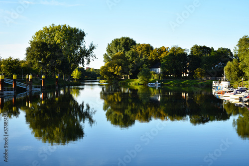 Nienburg marina harbor view at Weser river between green fields with a tree reflection on water