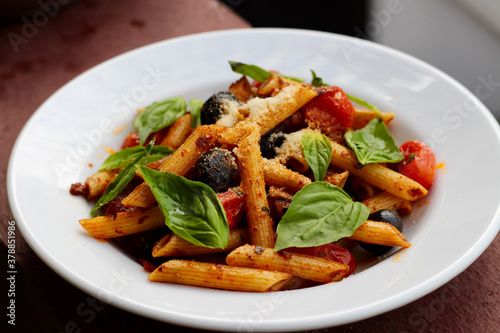 Penne pasta with black olives, grilled cherry tomatoes, fresh Italian basil, and sun-dried tomato pesto.
