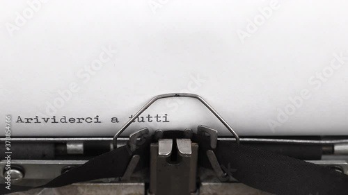 typing a message on italian arrivederci a tutti on a vintage typewriter close-up. translation from italian into english - goodbye everyone photo