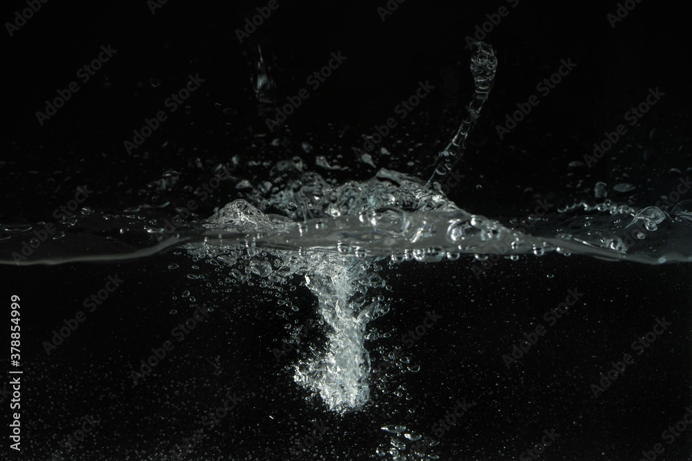 Obraz premium Water splashing as it's poured into aquarium tank, black background