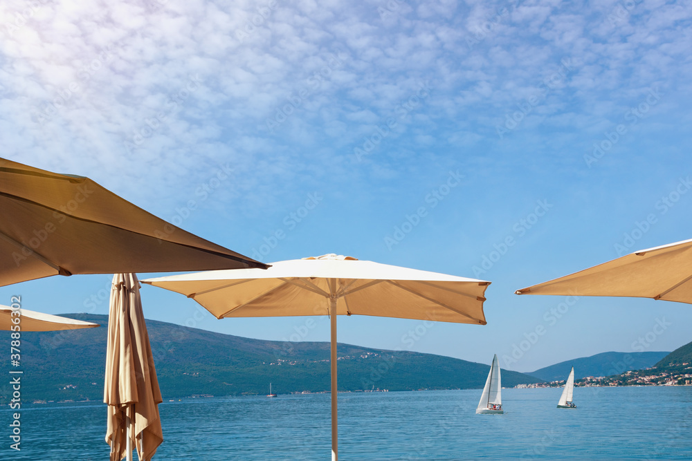 Vacation concept. Sun umbrellas against blue sky. Montenegro, Adriatic Sea. View of Kotor Bay near Tivat city Vacation concept. Sun umbrellas against blue sky. Montenegro, Adriatic Sea. View of Kotor Bay near Tivat city