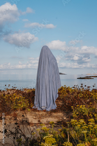 Woman in ghost costume standing on beach