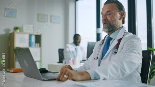 Wallpaper Mural Family Medical Doctor is Making a Video Call with Patient on Laptop Computer in a Health Clinic. Physician in Lab Coat is Talking About Health Issues and Diagnosis in Hospital Office. Torontodigital.ca