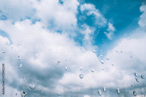 Wallpaper Mural Blue sky and fluffy white clouds through the wet window on a rainy day. Stay home in daylight during social isolation. Poor weather conditions. Moisture spray and rain drops on a glass surface indoors Torontodigital.ca