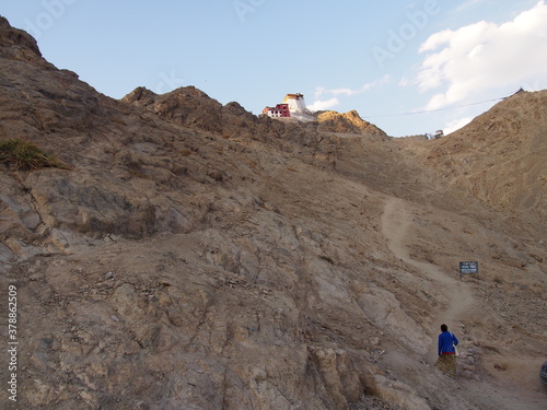 A woman climbs a mountain to reach Buddhist monastery (Namgyal Tsemo Gompa) around a historic town, Ladakh, Jammu and Kashmir, India photo