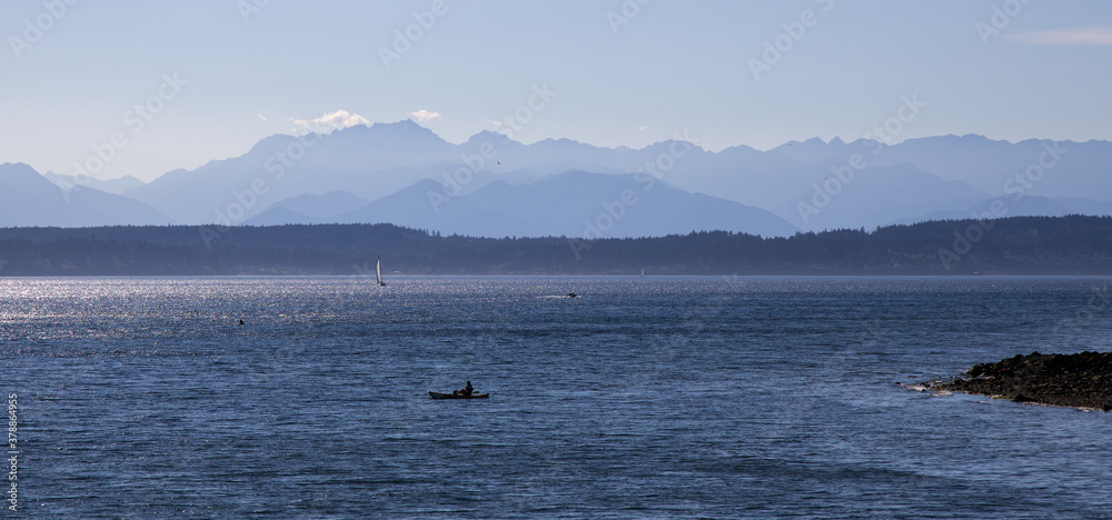Olympic Mountain Range as seen from Seattle with kayaker on Puget Sound in foreground
