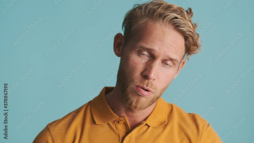 Young blond bearded man tiredly posing on camera over colorful background Young blond bearded man tiredly posing on camera over colorful background