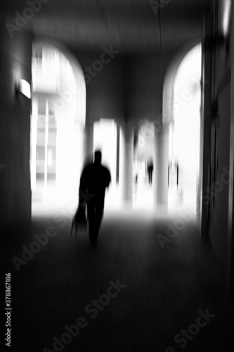 Motion blur image in black and white of man walking in urban environment.