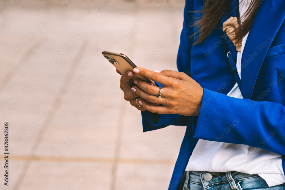 Business lady in blue blazer using smartphone. Woman reading information in internet or texting. Typing message or shop online or checking mobile application or social media