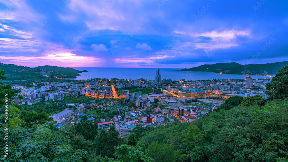Patong city in phuket thailand beautiful sunset sky with green leaves frame in the foreground.