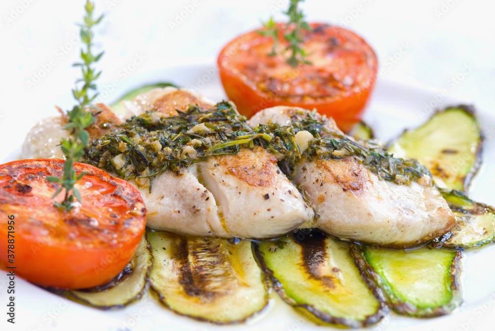 High angle view of grilled fish with zucchini and tomatoes