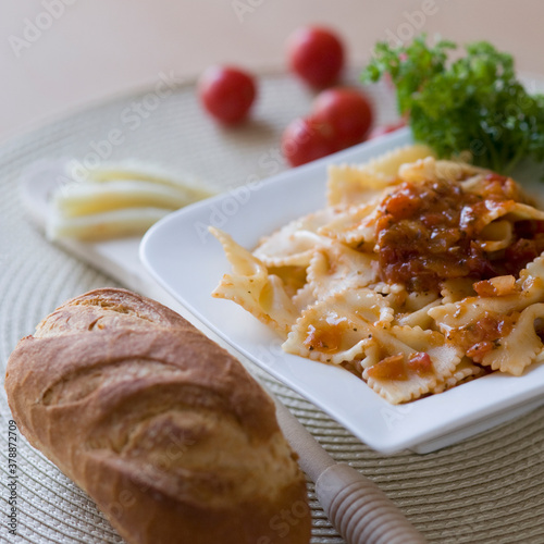 Close-up of a plate of bow tie pasta with a loaf of bread