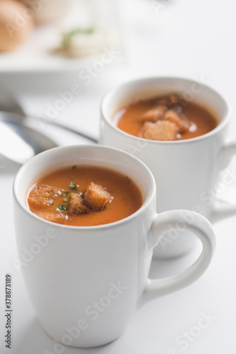 Close-up of two cups of tomato soup with bread cubes
