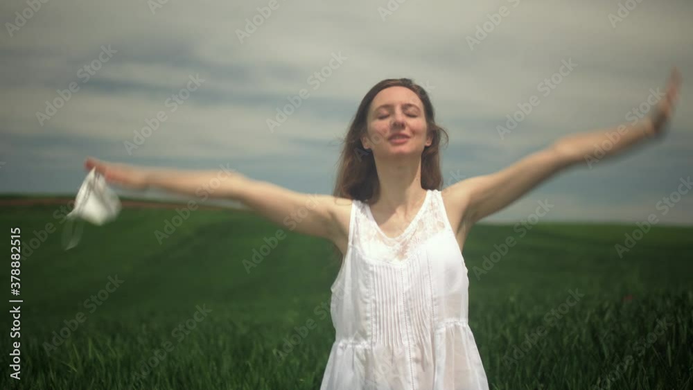Girl taking her mask off and taking a deep breath in a field. End of corona covid 19 pandemic concept. Girl taking her mask off and taking a deep breath in a field. End of corona covid 19 pandemic concept.