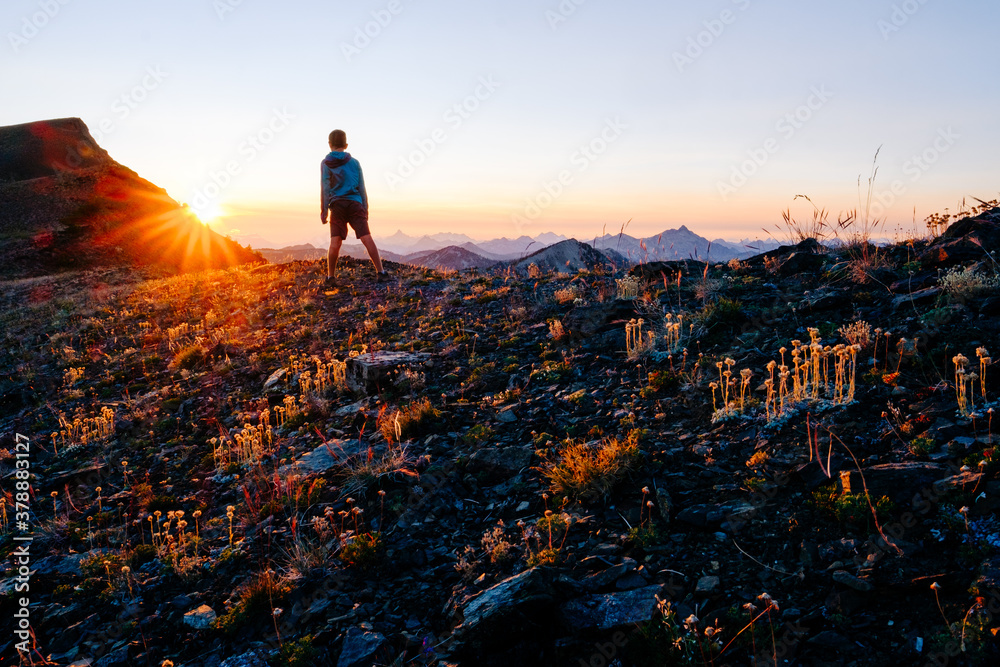 Active young man on a mountain summit at sunset