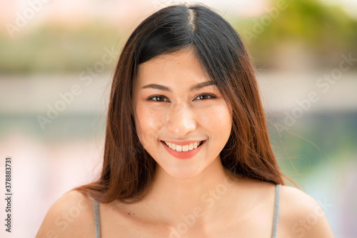 Beautiful young asian woman with natural make up looking at camera and smiling.