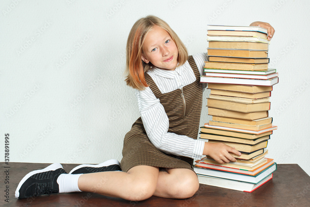 A teenage girl sits at the table near the books.