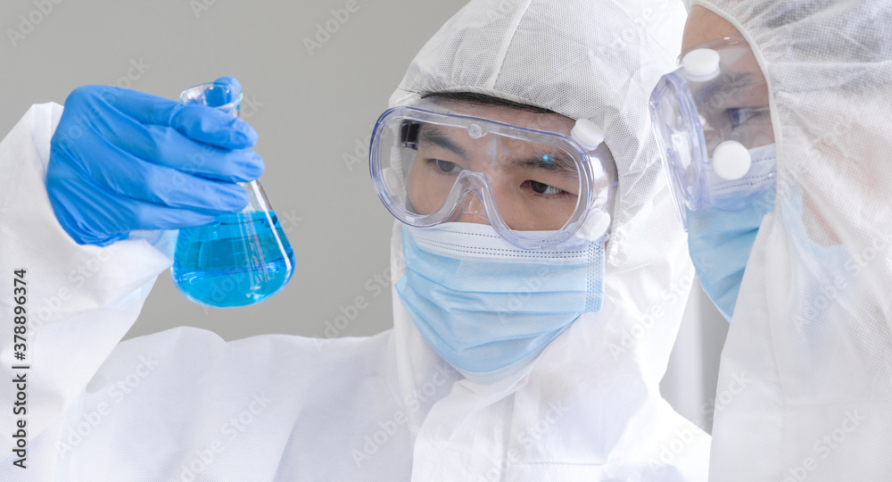 Two Scientists discuss about blue liquid chemical in Erlenmeyer flask. Two Scientists discuss about blue liquid chemical in Erlenmeyer flask.